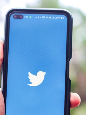 Hand of man using Twitter in Android smartphone with icons of social media on screen, smartphone life style, smartphone era, smartphone in everyday life.